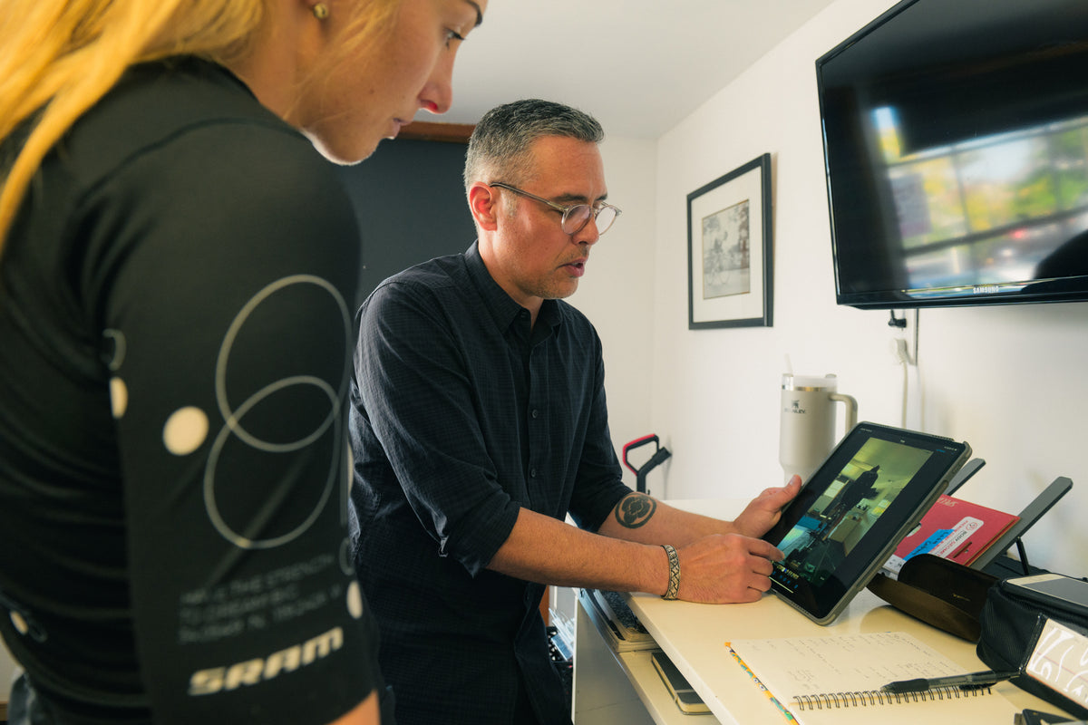 Two people working together on a tablet in  the Cadence bike fit studio.